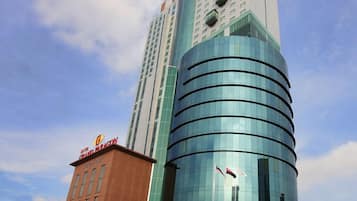 A hotel with a modern glass facade, a prominent sign at the top, and a flat-roofed structure at the base.