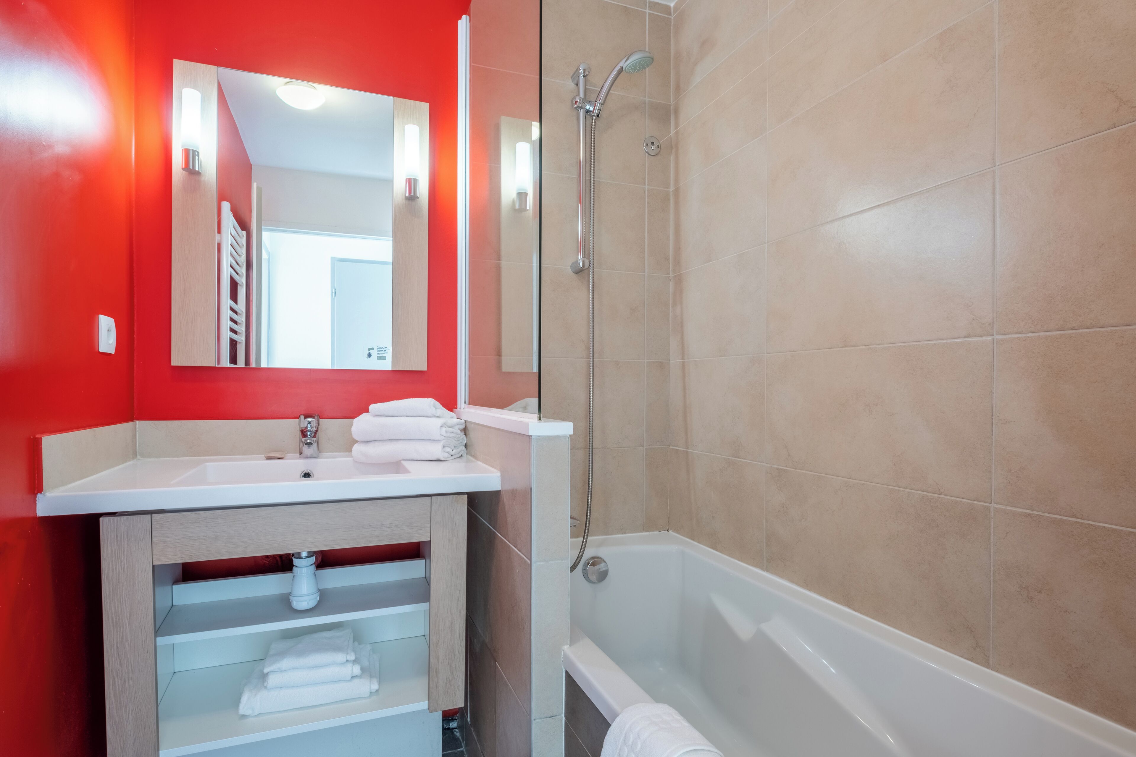 A bathroom with a white sink, mirror, and shower.