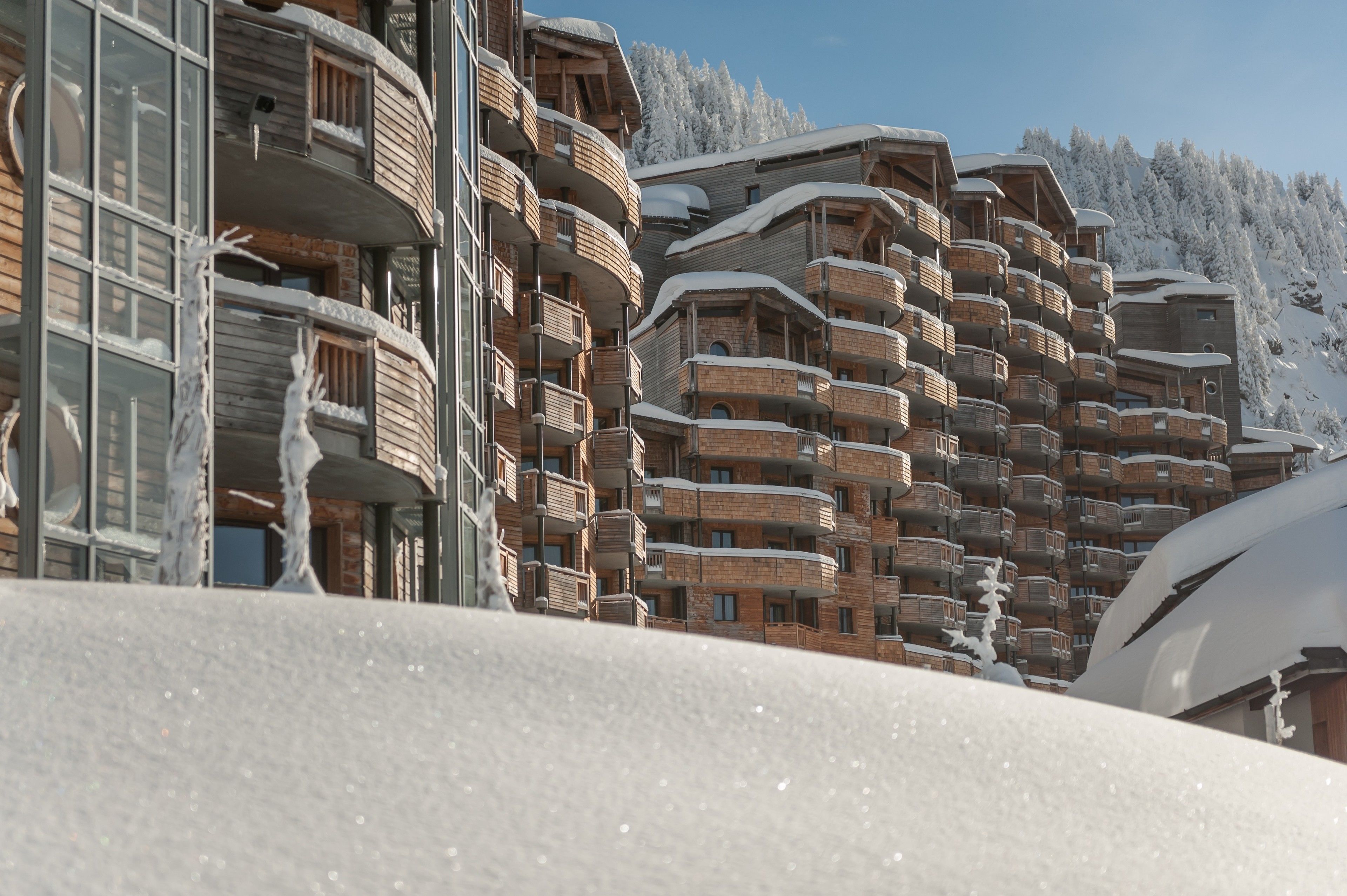 A multi-story hotel with balconies, wooden exterior, and snow-covered surroundings.