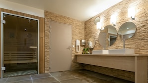 A modern bathroom with a stone wall, a large mirror, and a glass door leading to a shower area. - Résidence Pierre & Vacances Atria Crozats (Avoriaz)