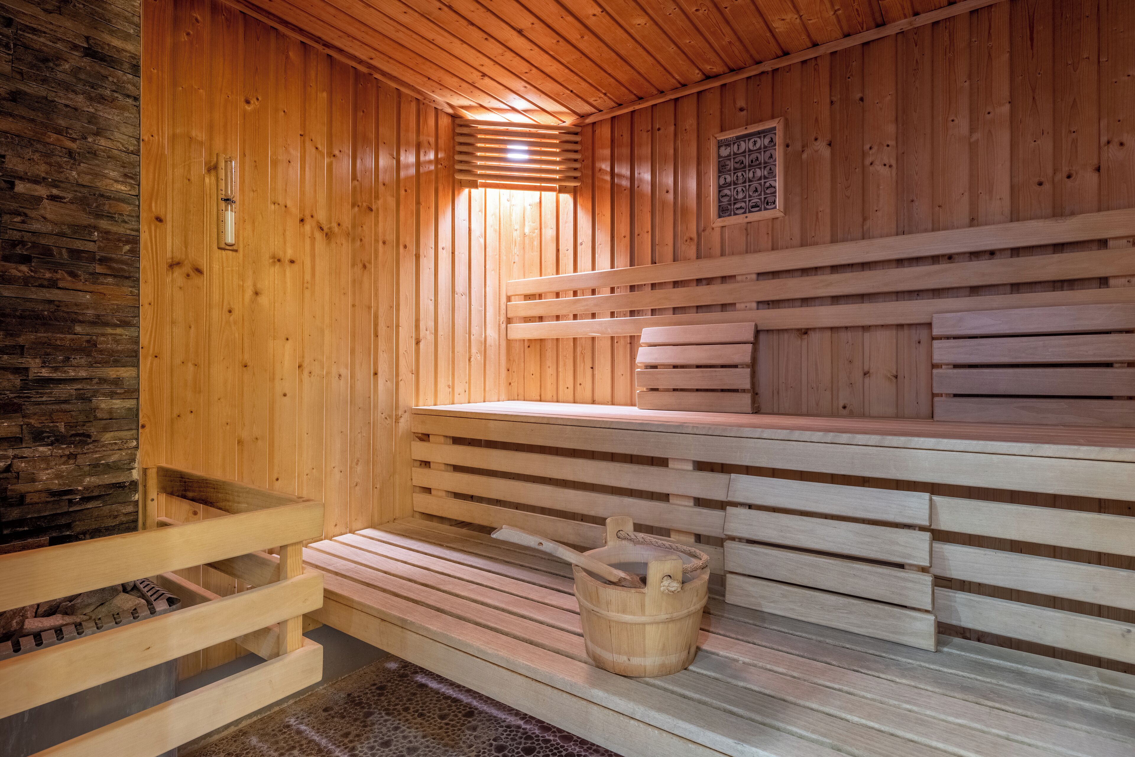 Een houten sauna met banken en een emmer.