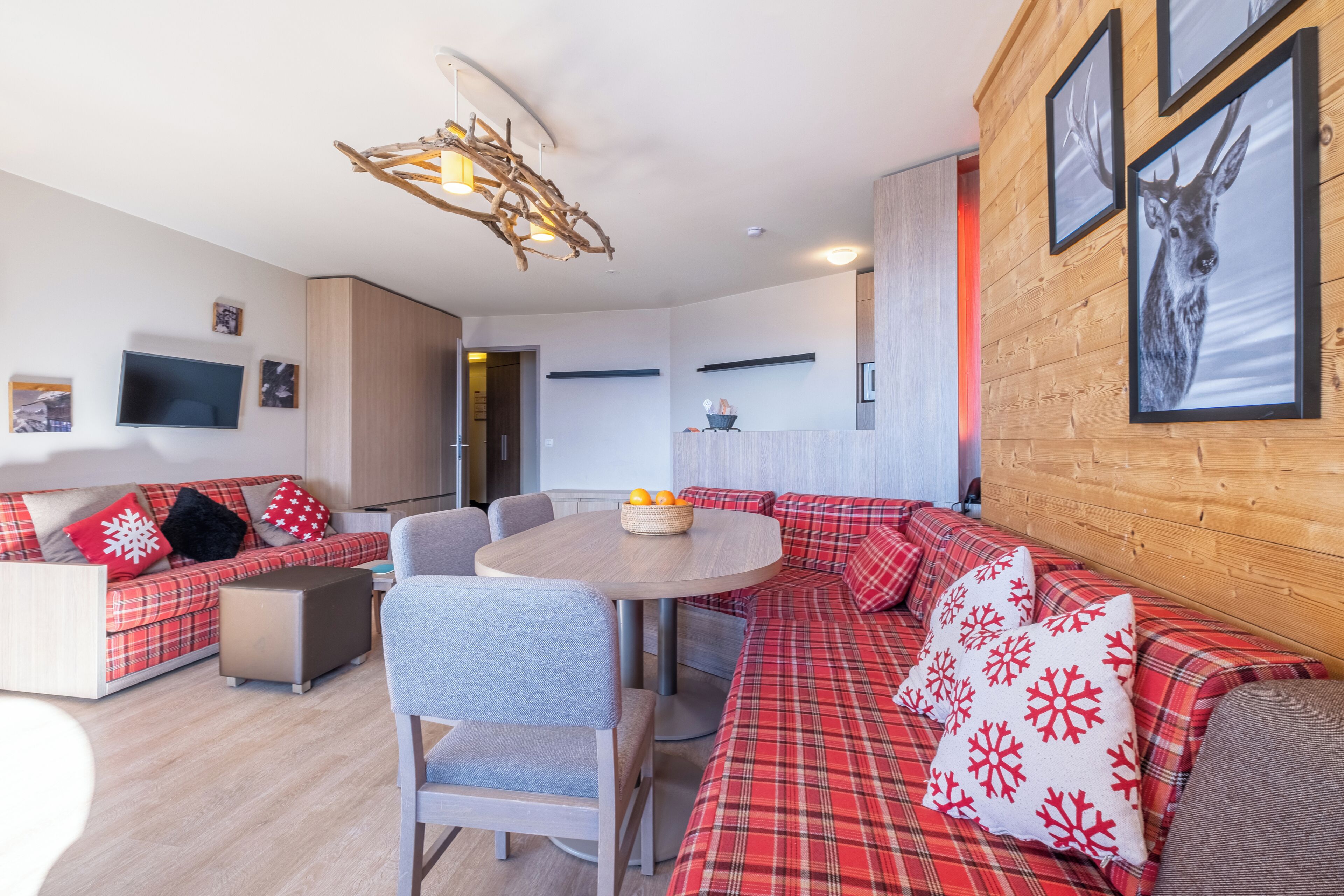 A modern living room with a sofa set, a round table, and a mounted television.