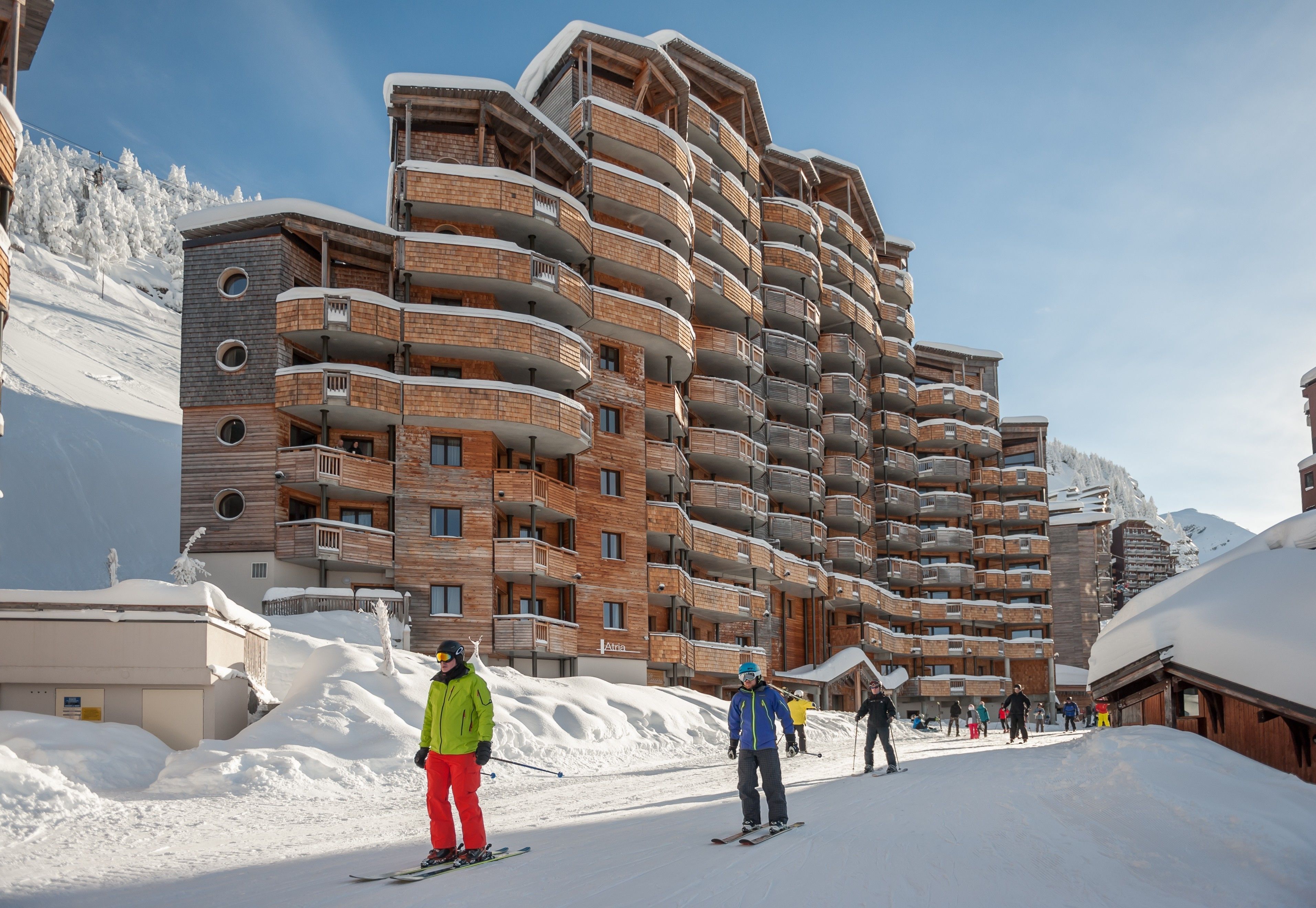 En bygning med flere etager og balkoner, med skiområder i baggrunden og snærede omgivelser.