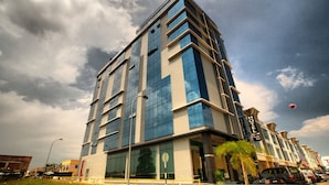 Un hotel moderno con fachada de vidrio, varios pisos y un llamativo letrero que dice 'HOTEL'.