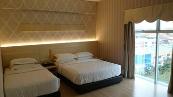A hotel room with two beds, a large window with curtains, and a patterned wallpaper.
