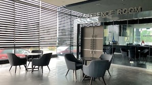Una sala de conferencias moderna con ventanas amplias, sillas negras y suelo de mármol.