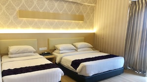 Habitación de hotel con dos camas, una mesita de noche con un teléfono y una lámpara de pared.