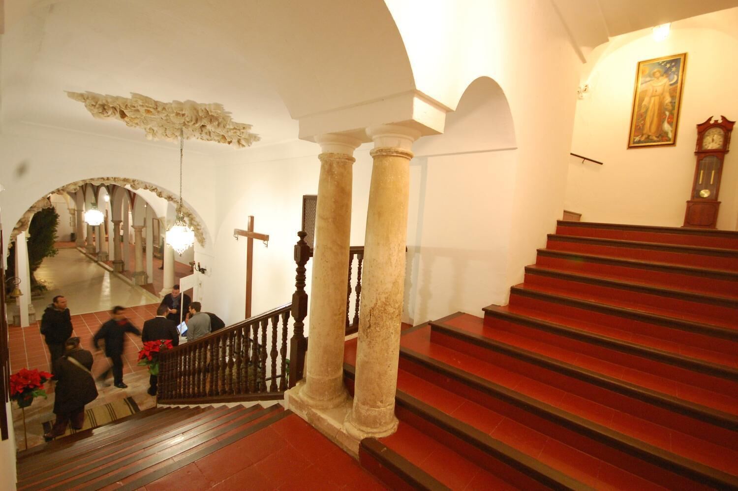 Una escalera con peldaños rojos, columnas blancas y una araña.