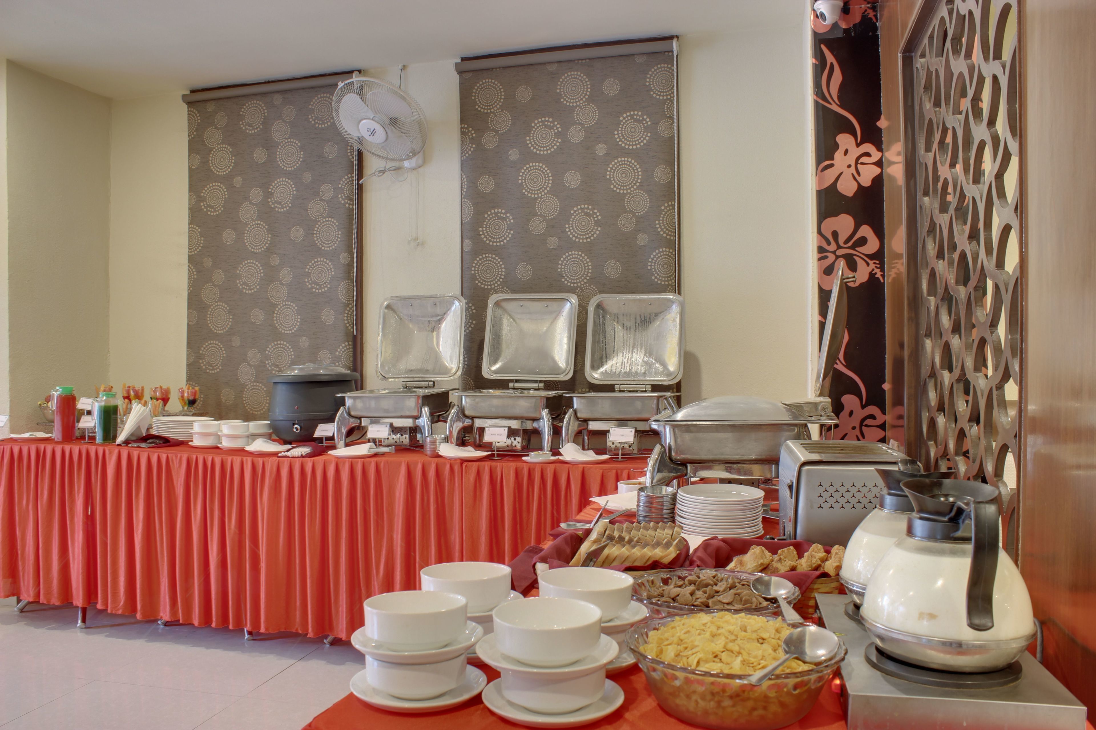 A buffet setup with multiple serving stations, including bowls of food, plates, and serving utensils.