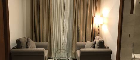 A living room with two sofas, a glass coffee table, and a lamp.