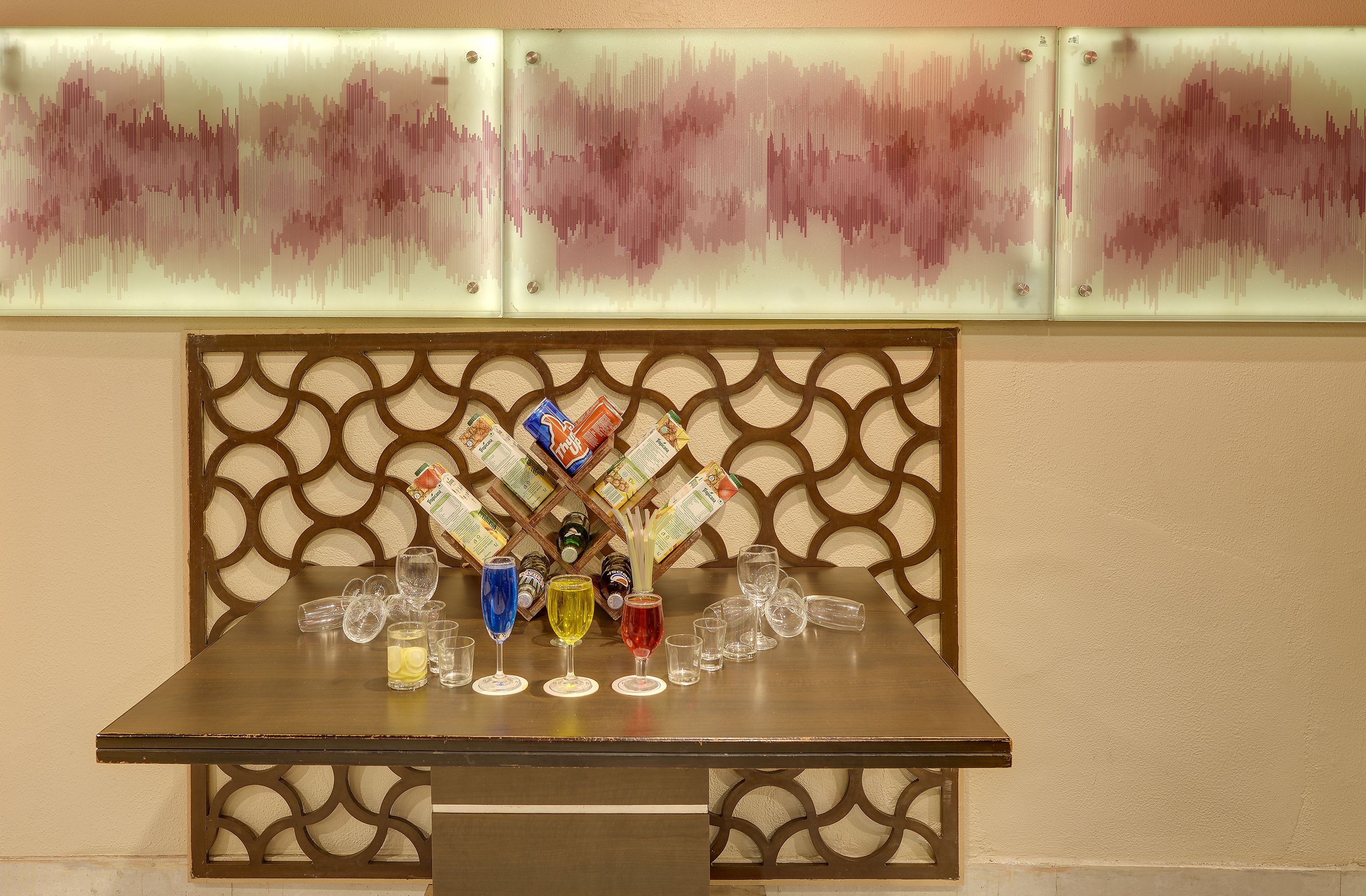 A bar area with a decorative partition, glasses, and bottles on the counter.