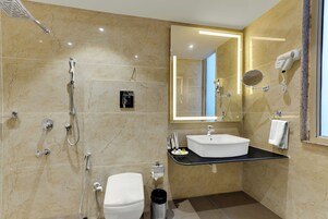 Un baño moderno con ducha, inodoro, lavabo y un secador de pelo en la pared.