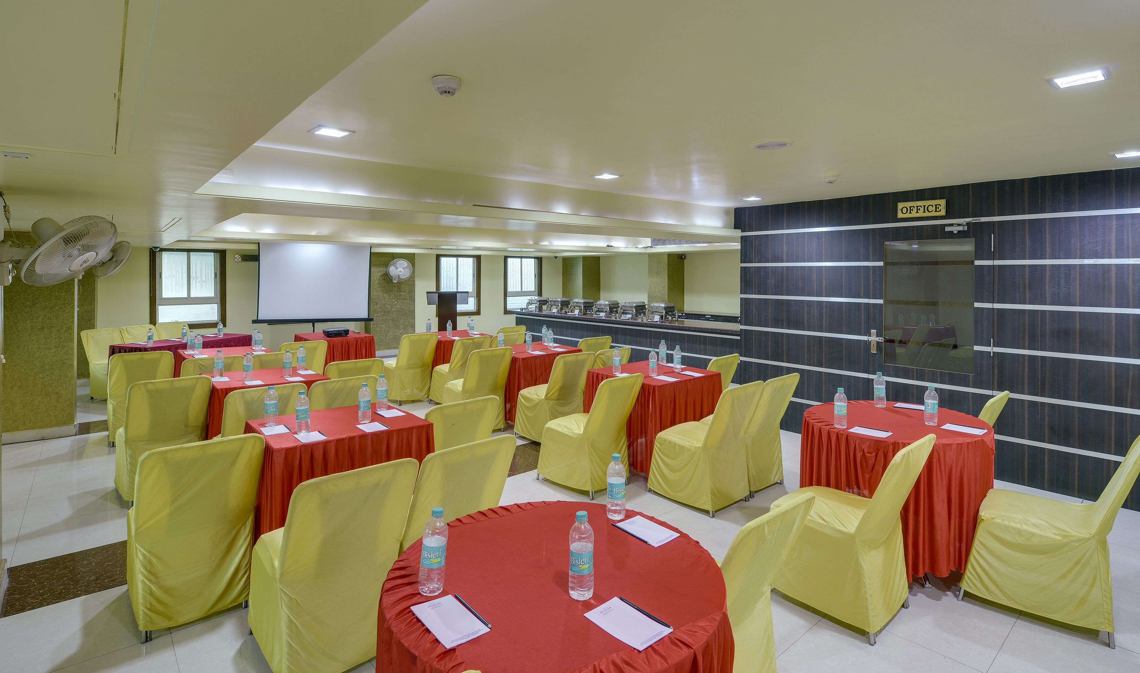 A conference room with multiple tables and chairs, equipped with water bottles and name cards.