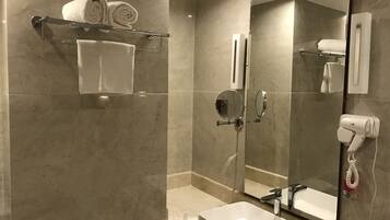 Un baño moderno con un espejo grande, un lavabo, un perchero con toallas y un secador de pelo.