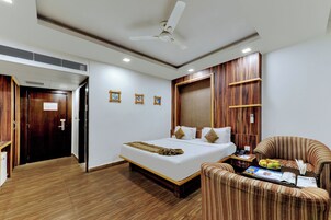 Una habitación de hotel con cama, sofá, mesa de comedor y un ventilador de techo.