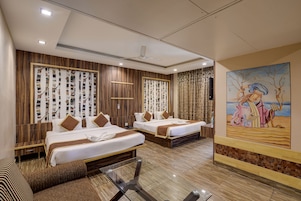 Habitación de hotel con dos camas, una mesita de vidrio y un mural en la pared.