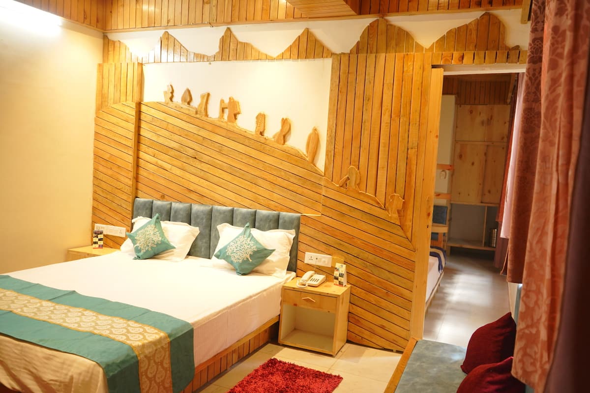 A bedroom with a wooden headboard, a bed with white bedding and decorative pillows, a nightstand with a phone, and a red rug.
