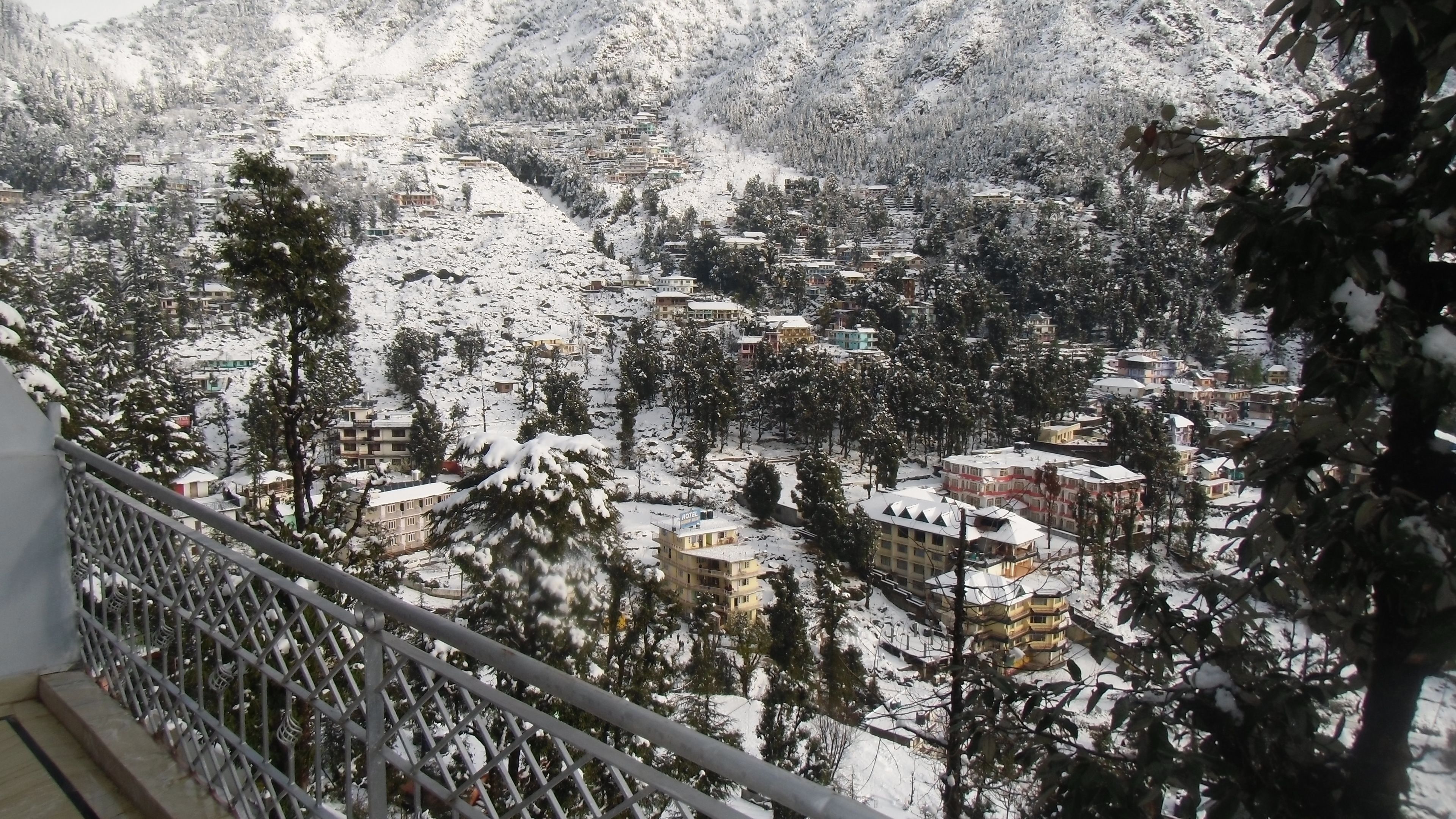 A snow-covered mountain village with buildings and trees.