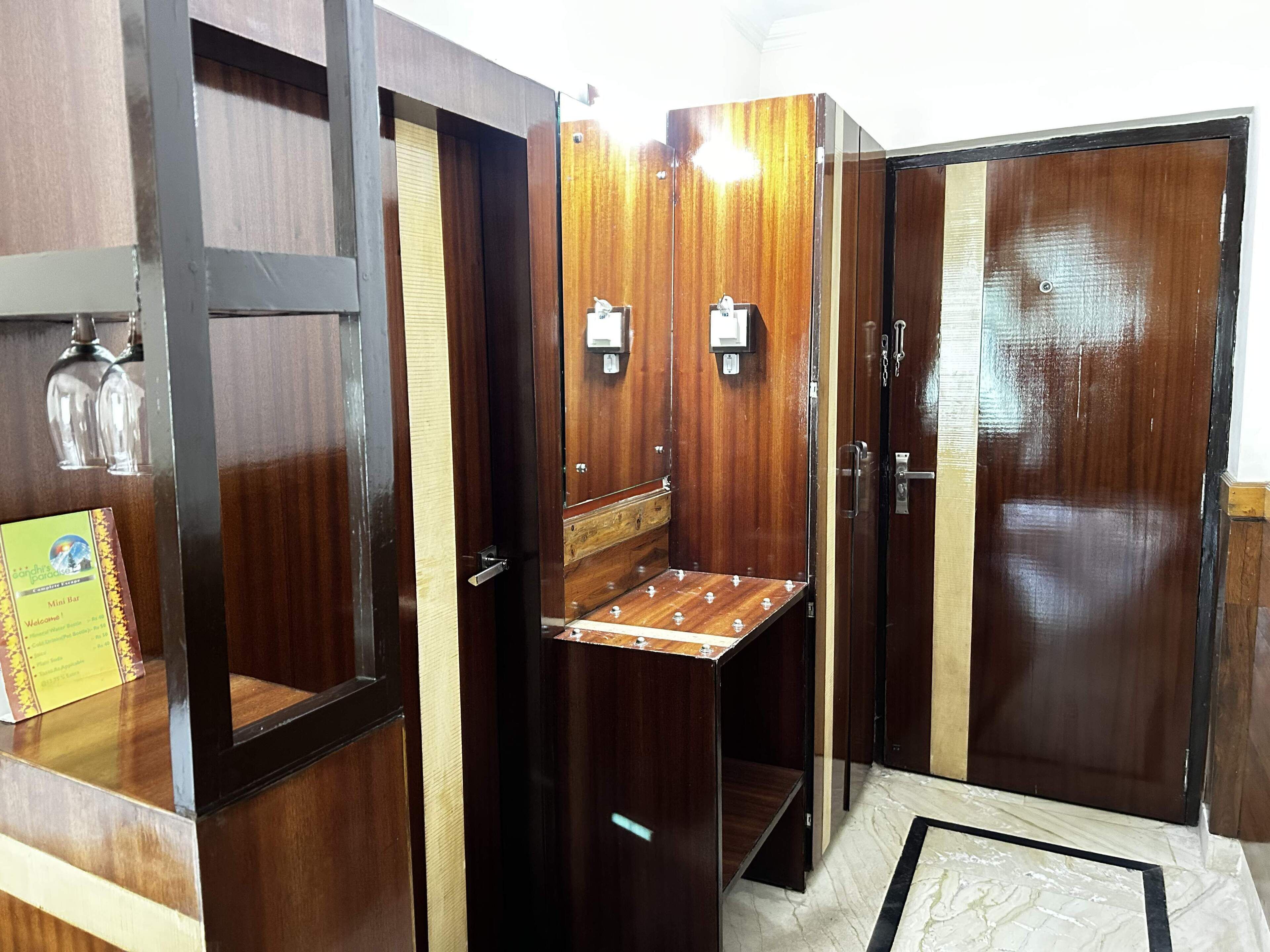 A compact, wooden-finished room with a small bar area, a mirror, and a door with a handle.