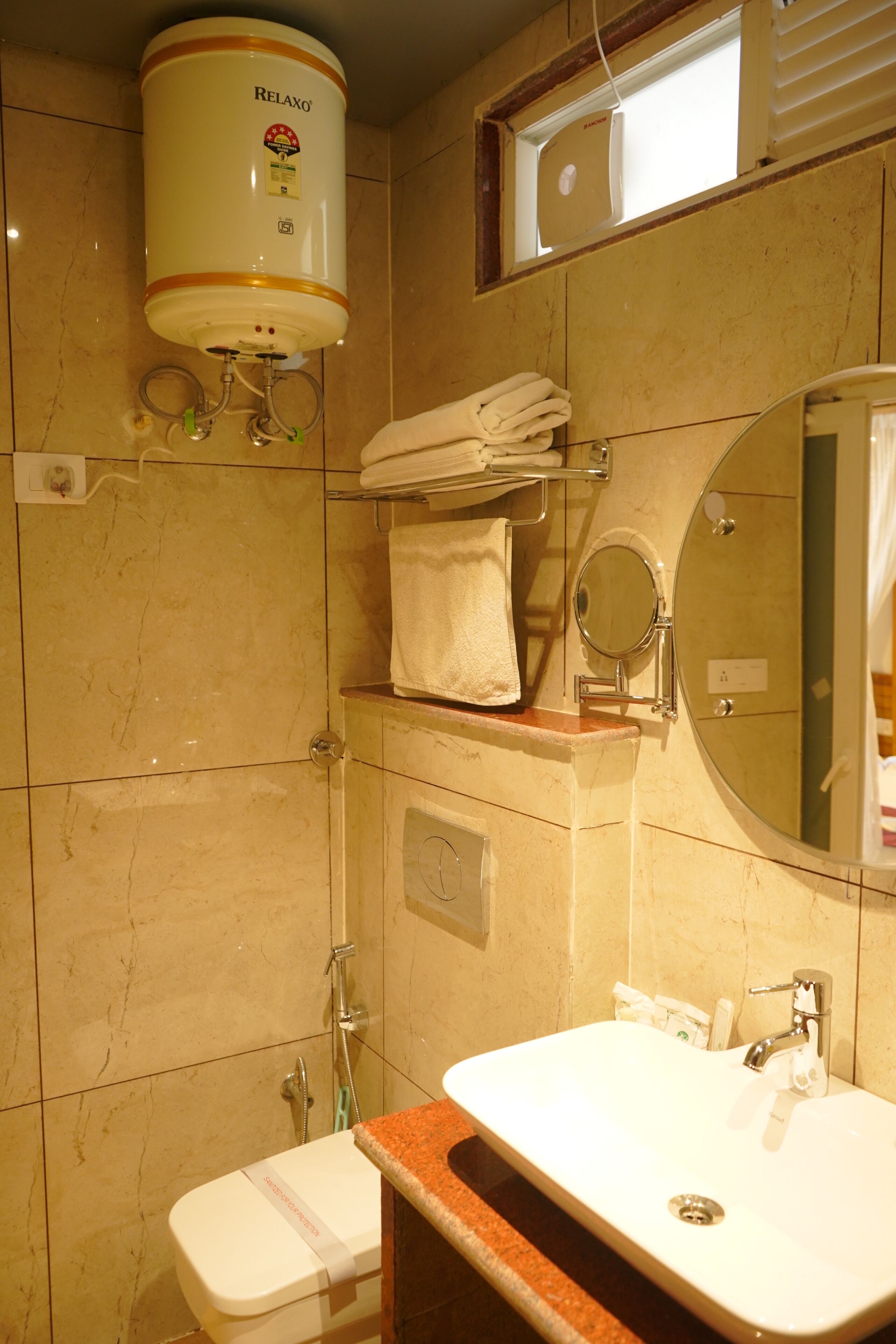 Un baño con inodoro, lavamanos, toallero y calentador de agua.