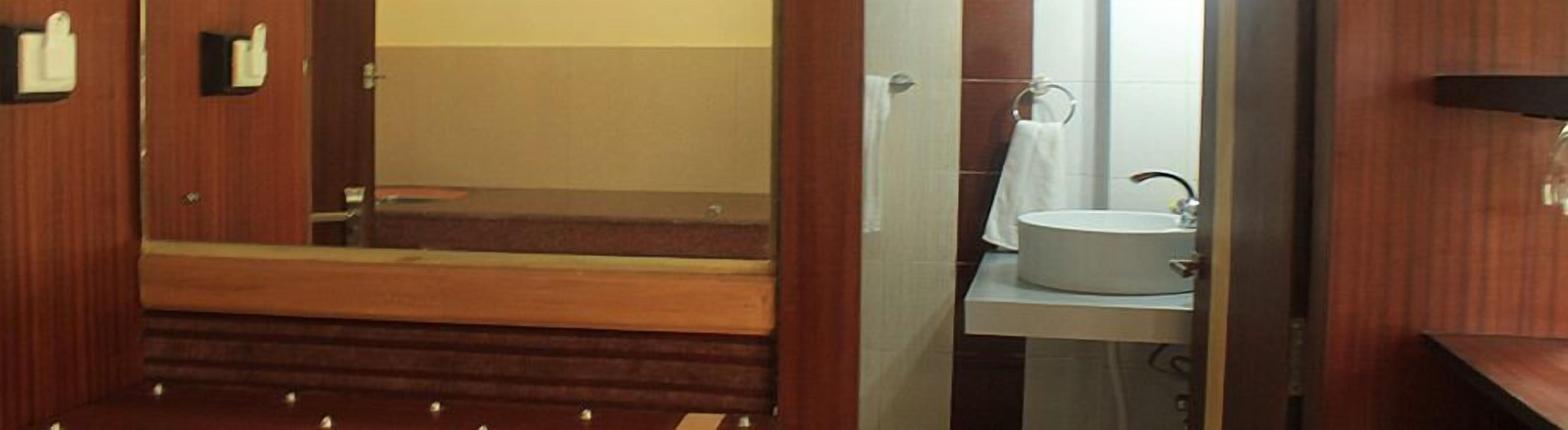 Un baño con un banco de madera, un lavabo y un espejo.