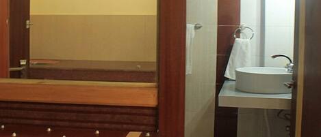 Un baño con un banco de madera, un lavabo y un espejo.