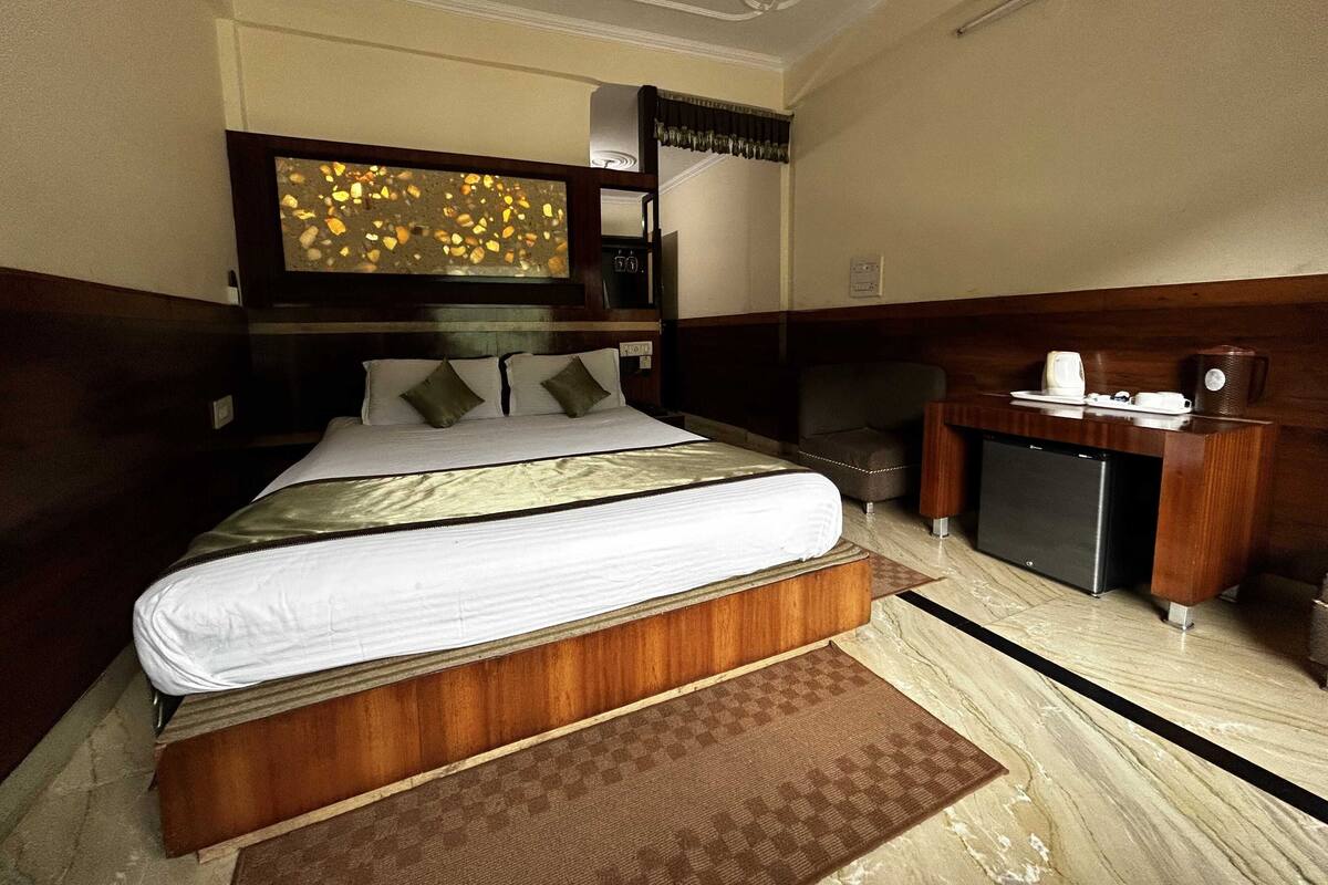 A hotel room with a large bed, a desk with a coffee maker, and a television on the wall.