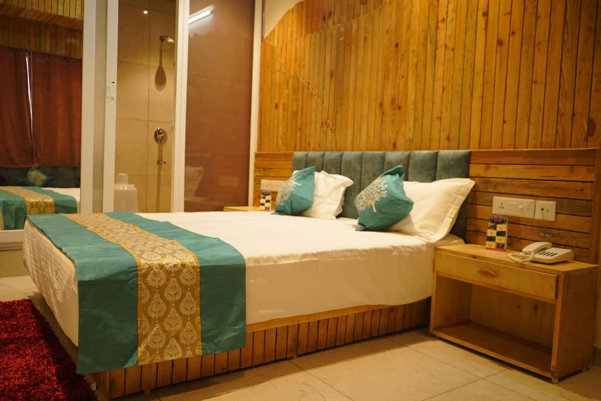 A neatly made bed with a patterned bedspread, a wooden headboard, and a bedside table with a telephone.