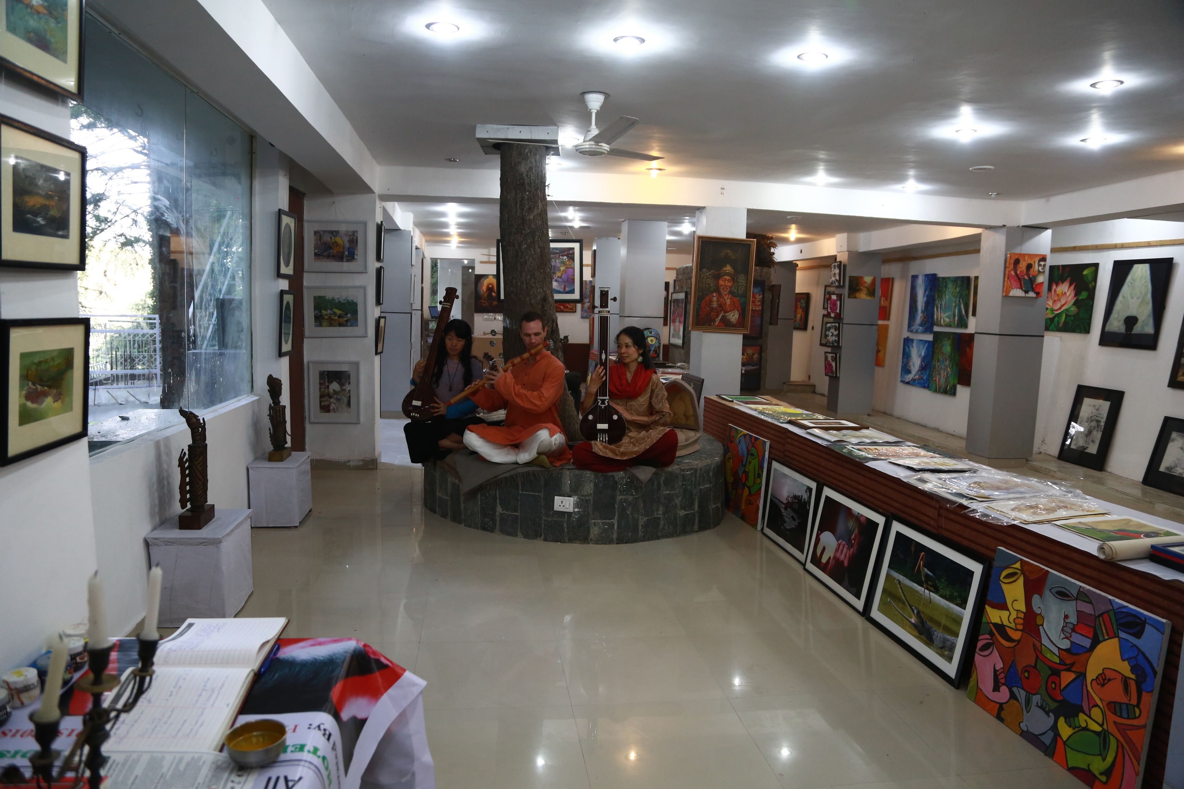 A modern art gallery with a central seating area, artworks on the walls, and a polished floor.