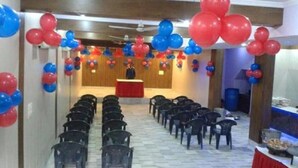 A room with rows of chairs facing a podium, decorated with red and blue balloons. - Hotel Landmark-Haridwar (Haridwar)