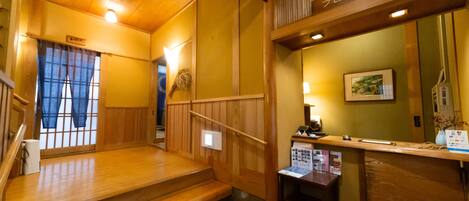 A wooden interior with a reception desk, a staircase, and a framed picture on the wall.