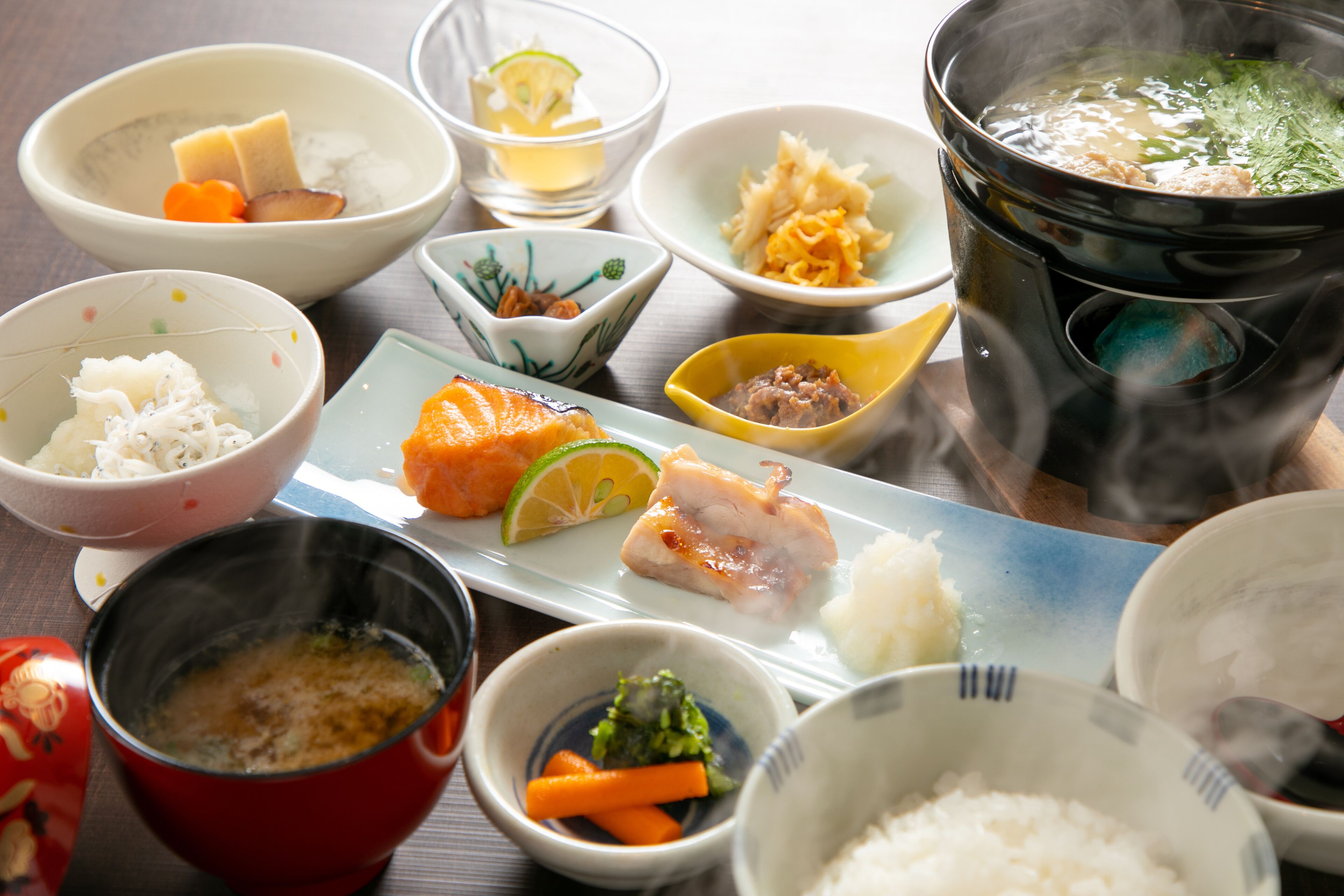 A variety of Japanese dishes including sushi, sashimi, and rice bowls, served on a wooden table.
