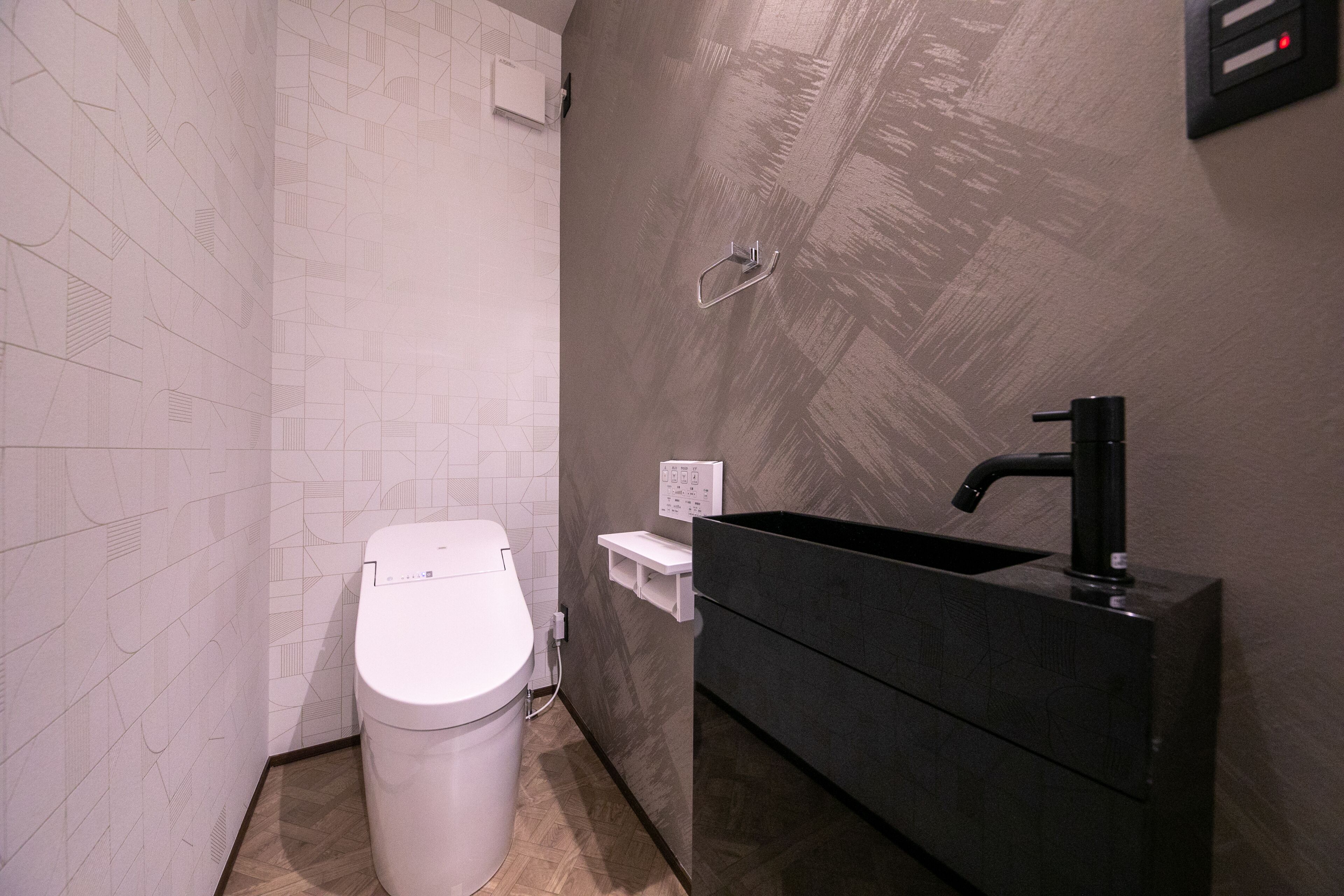 A modern bathroom with a white toilet, a black sink, and a wall-mounted towel rack.