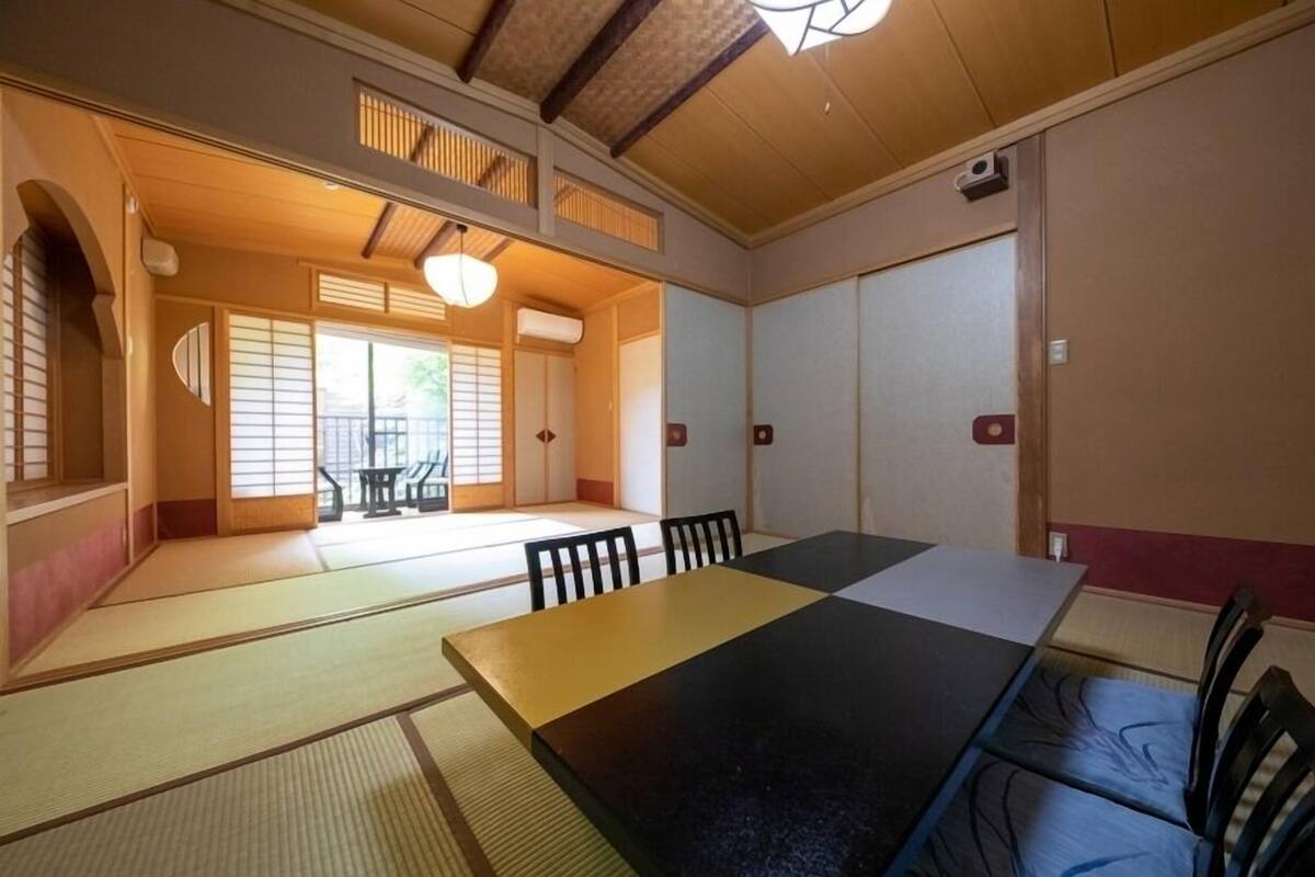 Una habitación japonesa tradicional con suelo de tatami, una mesa baja y puertas correderas.