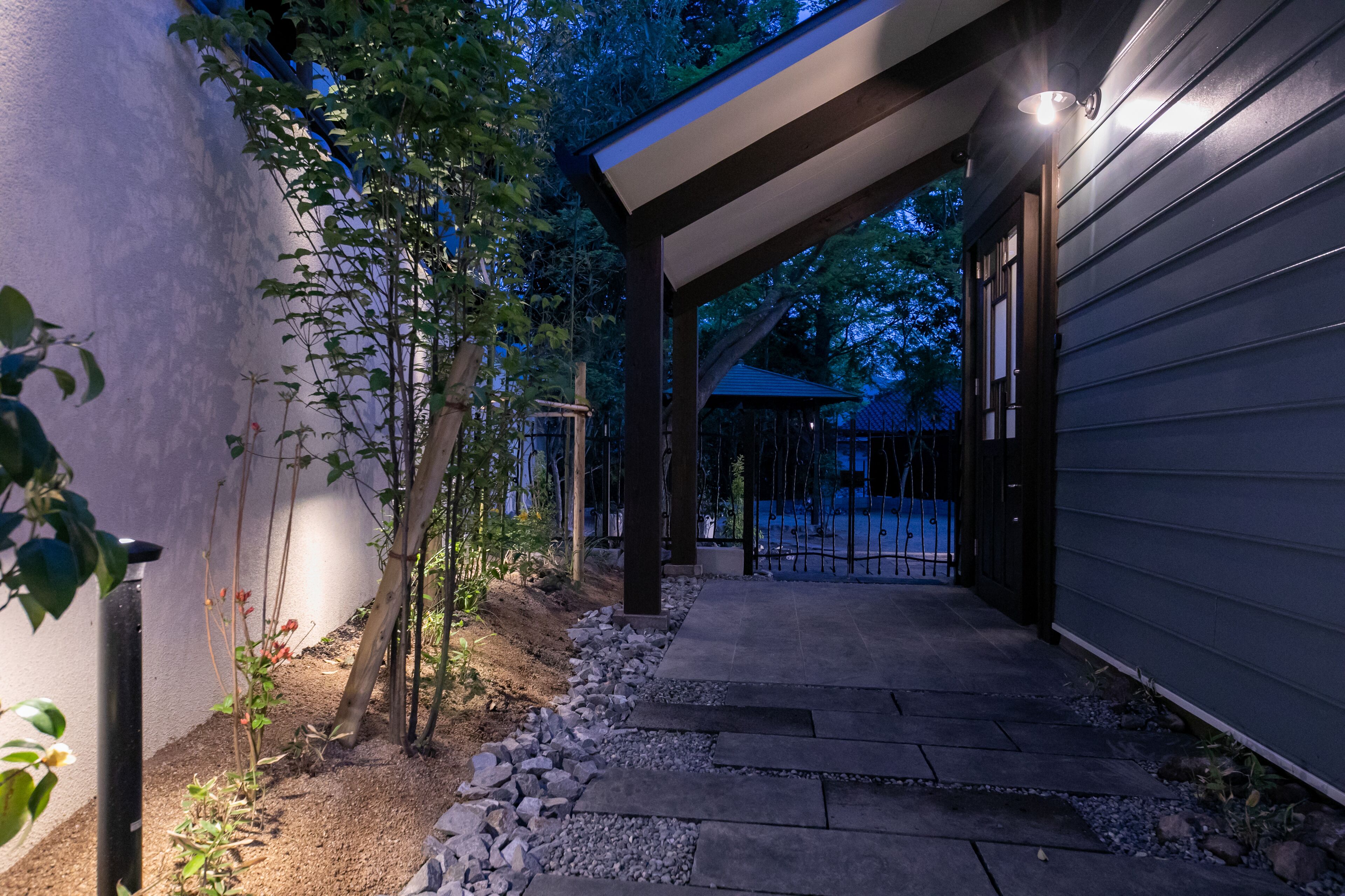 A covered outdoor pathway leading to a building with a dark exterior and a light fixture above the entrance.