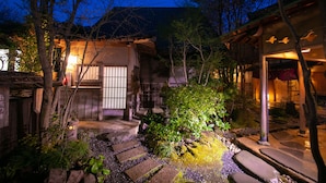 A traditional Japanese garden with stone pathways, moss-covered rocks, and wooden structures. - Oyado Ichizen (Yufu)