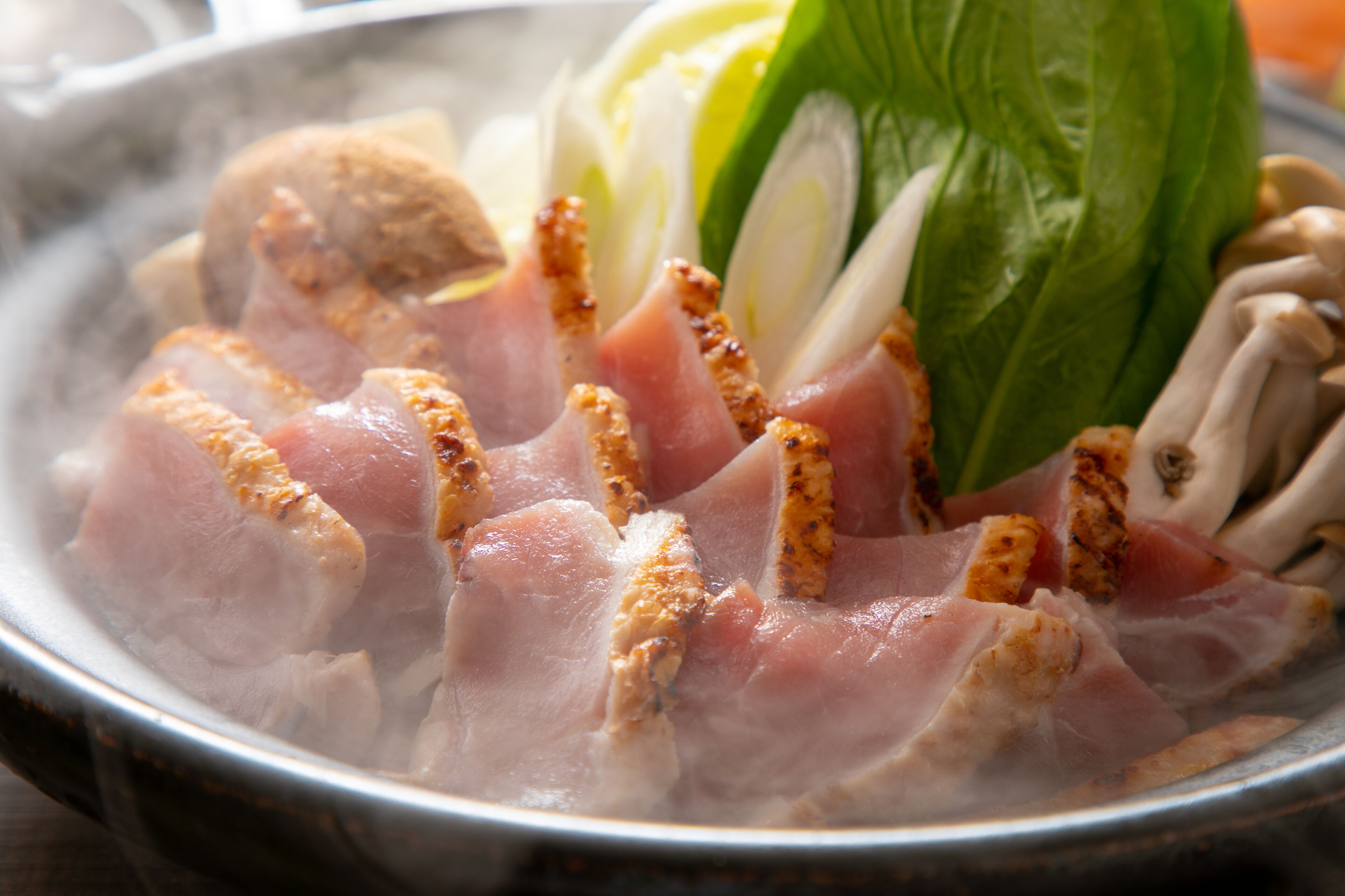 A bowl of food with sliced meat and vegetables.