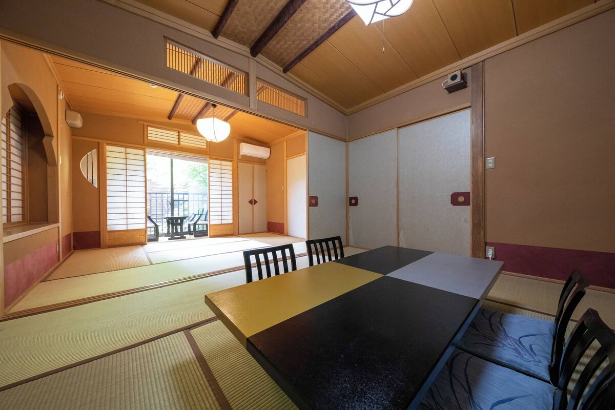Una habitación japonesa tradicional con suelo de tatami, una mesa baja y puertas correderas.