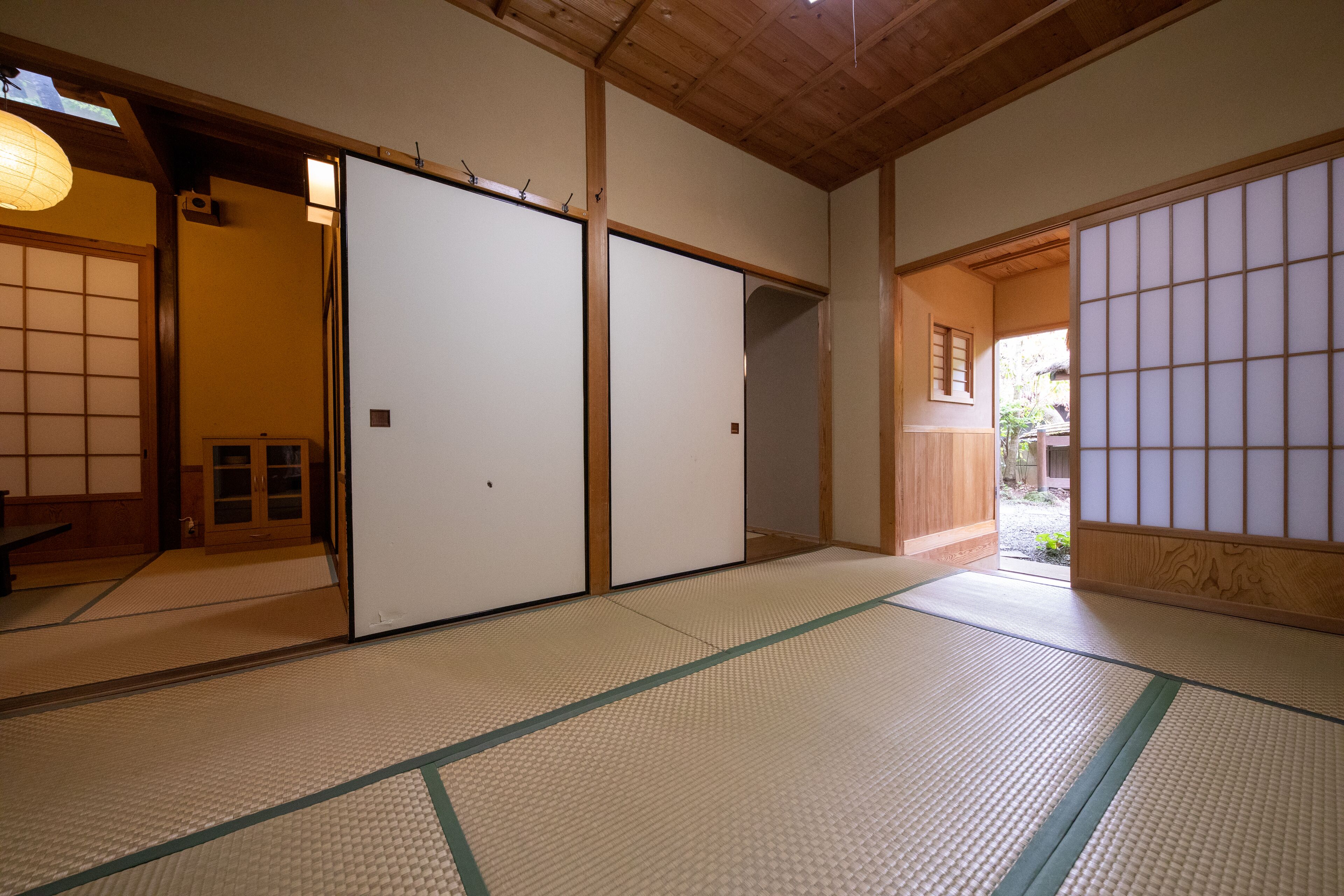 A traditional Japanese room with tatami flooring, sliding doors, and a wooden ceiling.