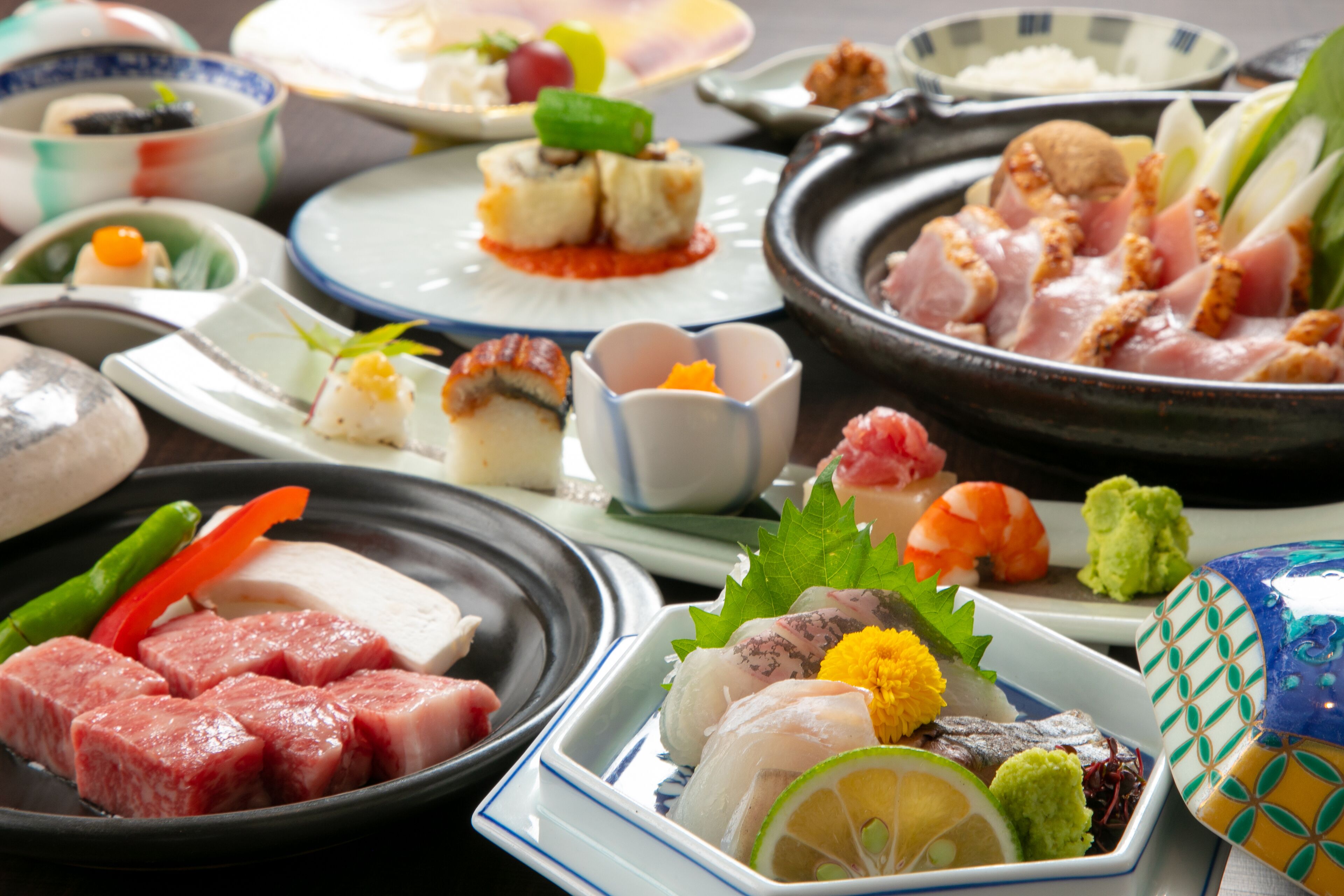 A variety of dishes on a table, including sushi, sashimi, and other Japanese cuisine.