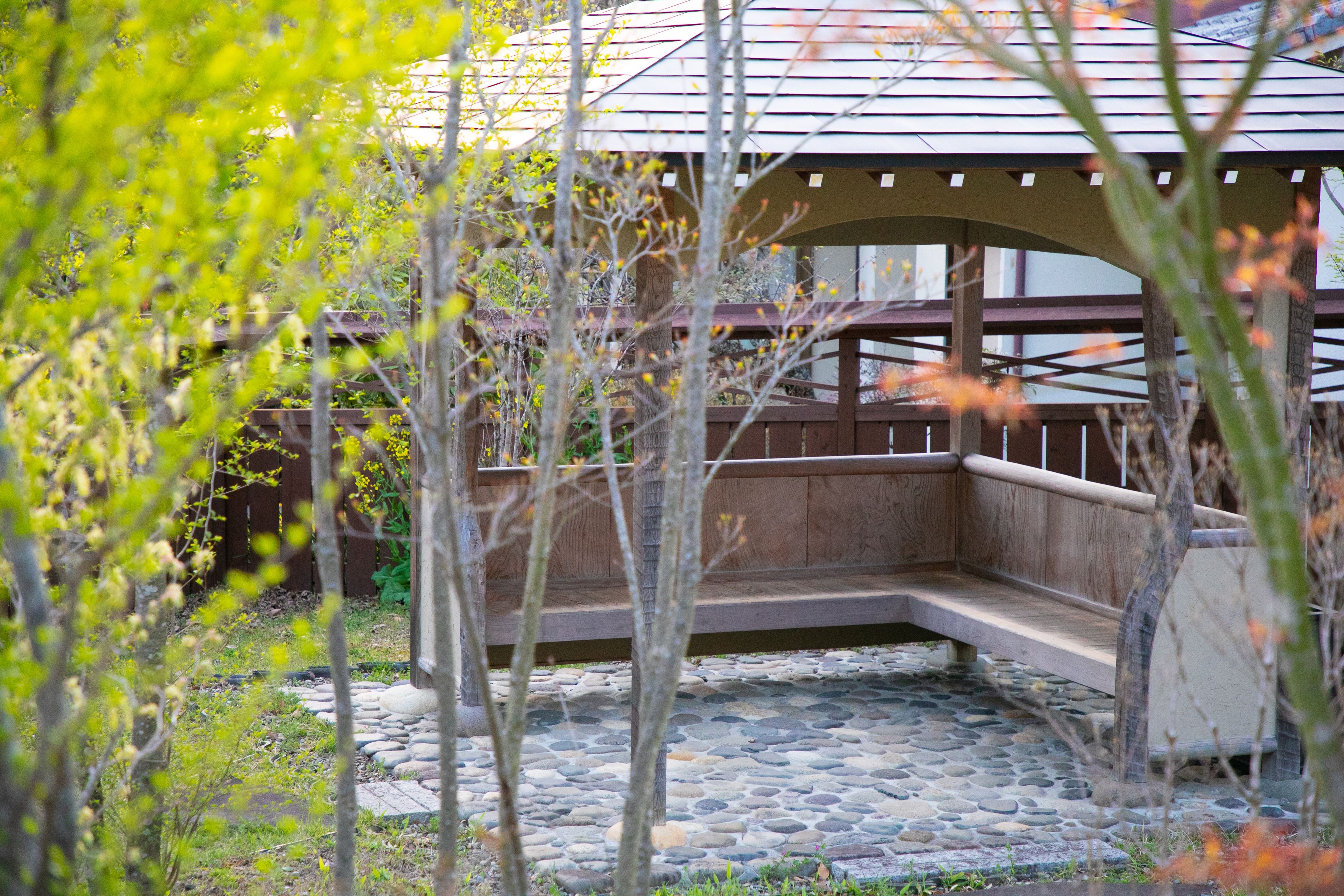 A covered outdoor seating area with stone flooring and wooden railings.