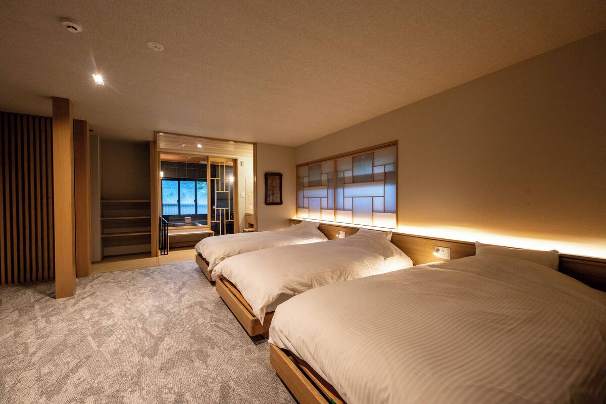 Habitación de hotel con dos camas, vistas al exterior y una escalera que sube a un nivel superior.