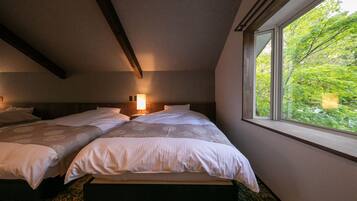 A bedroom with two beds, a window with a view of trees, and a wooden ceiling beam.