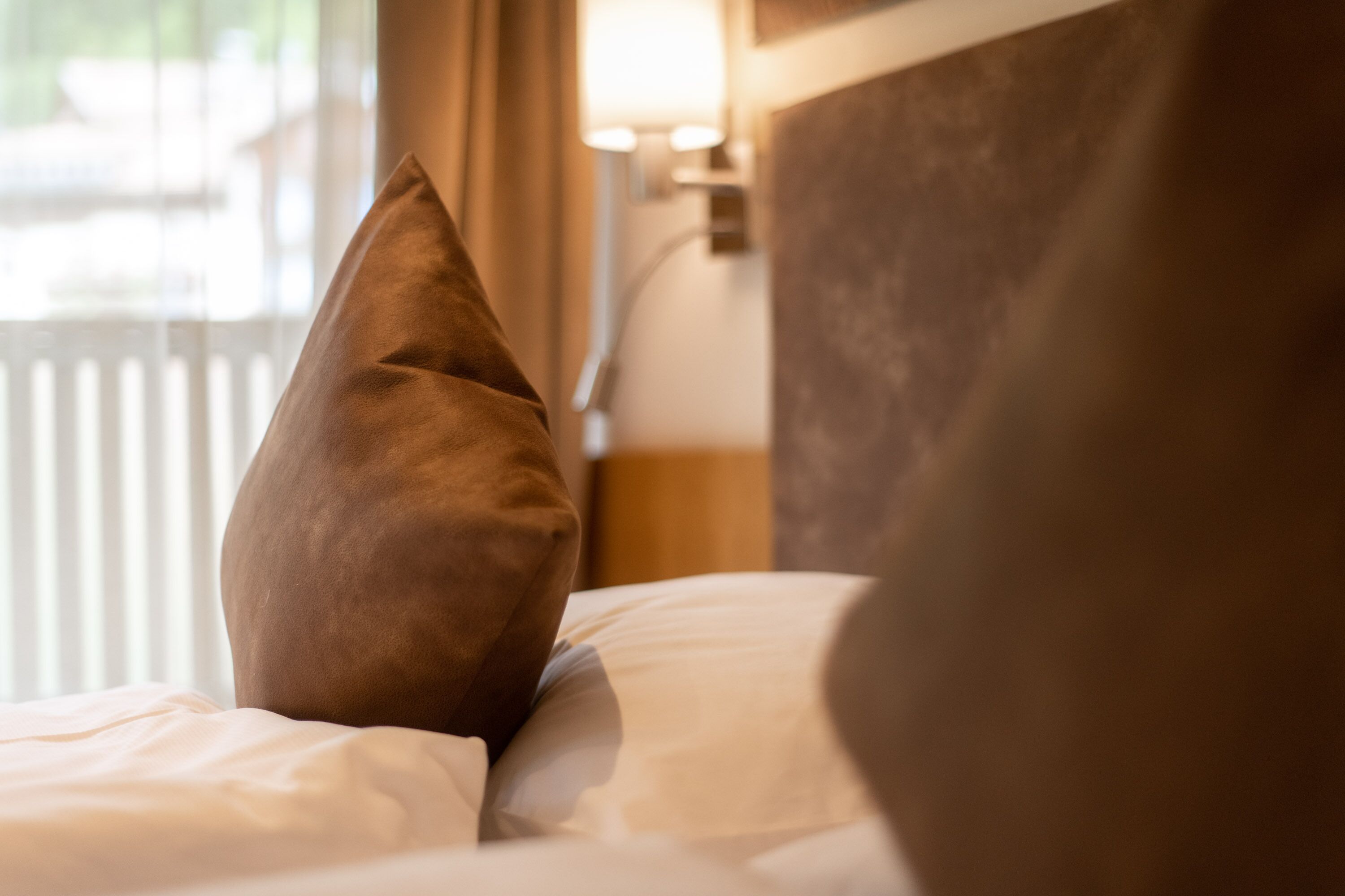 A close-up of a bed with a brown pillow and a white pillow.