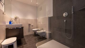 A modern bathroom with a glass shower enclosure, a bathtub, a toilet, and a sink.