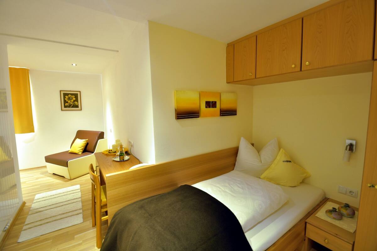 A hotel room with a bed, a desk, a chair, and a small table.