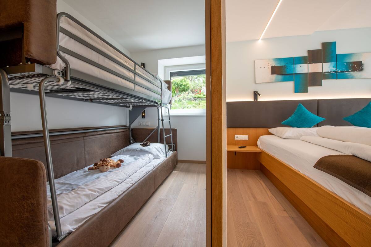 A bunk bed room with a window, a bedside table, and a wall art piece.