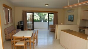 A compact living space with a dining area, kitchenette, and a sliding glass door leading to a balcony. - Niki Hotel Apartments (Rhodes)