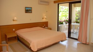 A bedroom with a bed, bedside tables, a nightstand, a lamp, an air conditioner, and a view of an outdoor area with a table and chairs. - Niki Hotel Apartments (Rhodes)