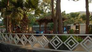 Une zone de villégiature dotée d’une piscine, de chaises longues et d’un pavillon à toit de chaume.